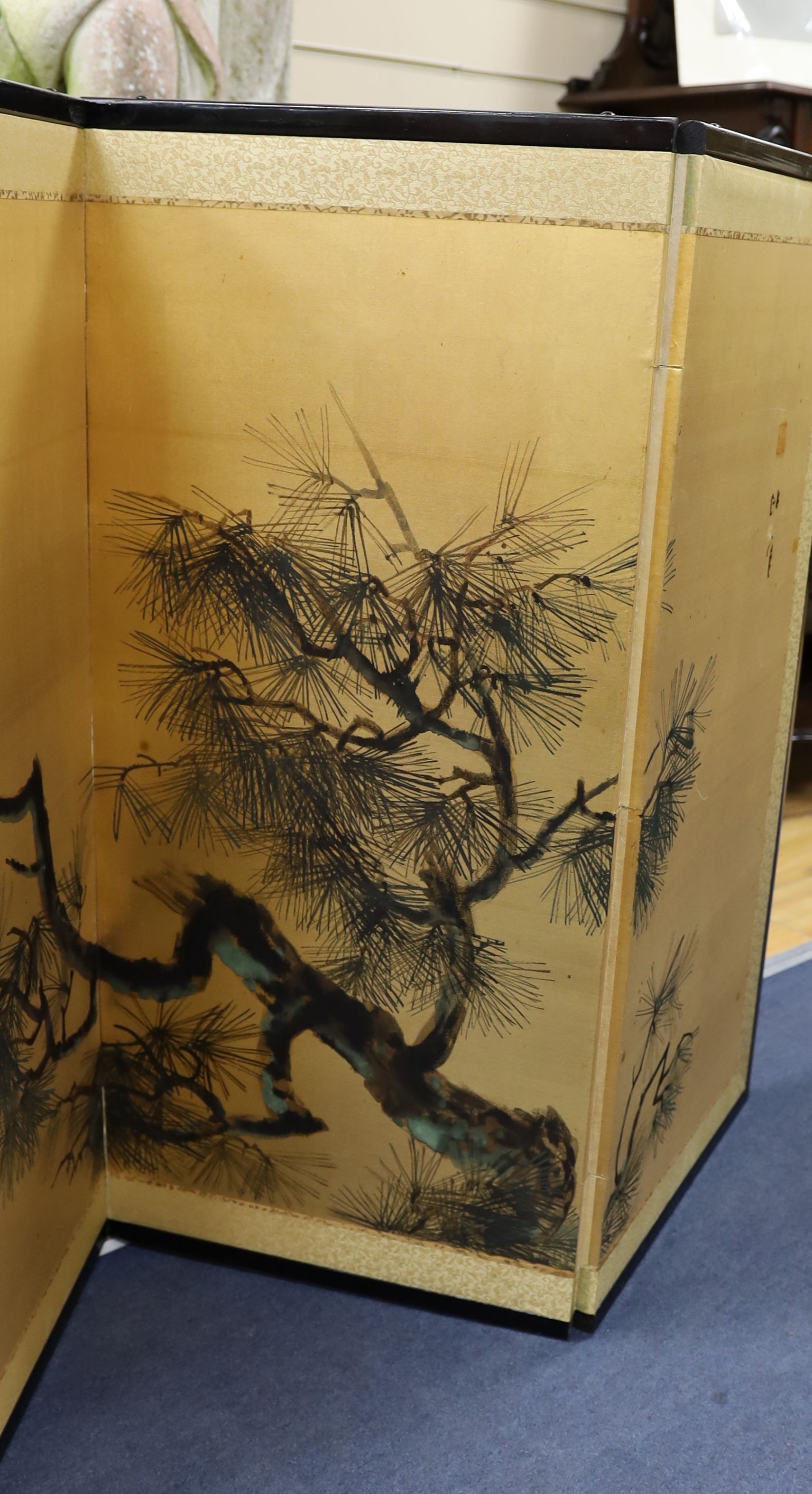 A Japanese gilt screen decorated with pine branches together with a Chinese rectangular wall mirror and a low table.